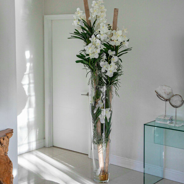 Weiße Vanda-Orchideen und Treibholz in einem großen konischen Glaszylinder