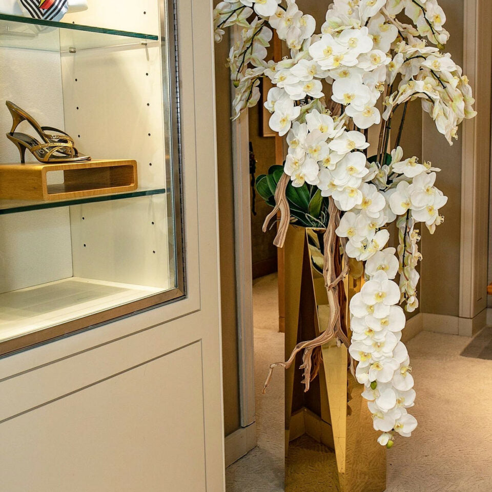 Kaskadierende Phalaenopsis-Orchideen in einem goldenen Prismentopf